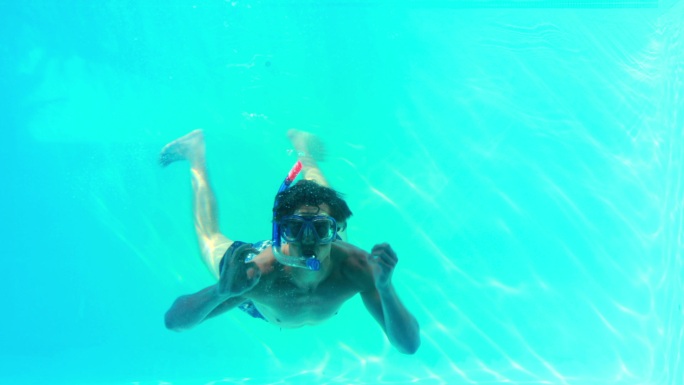 假日里，一名男子戴着面罩在游泳池里跳来跳去，对着镜头挥手