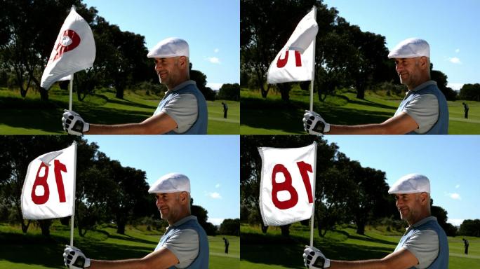 微笑的高尔夫球手举着第十八洞旗在高尔夫球场的慢动作