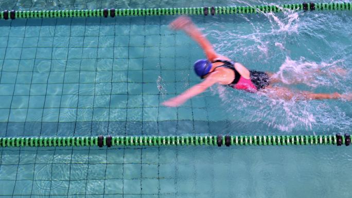 健身女子在休闲中心的游泳池里蝶泳