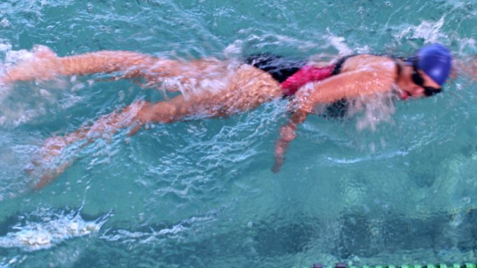健身女子在休闲中心的游泳池里做前泳