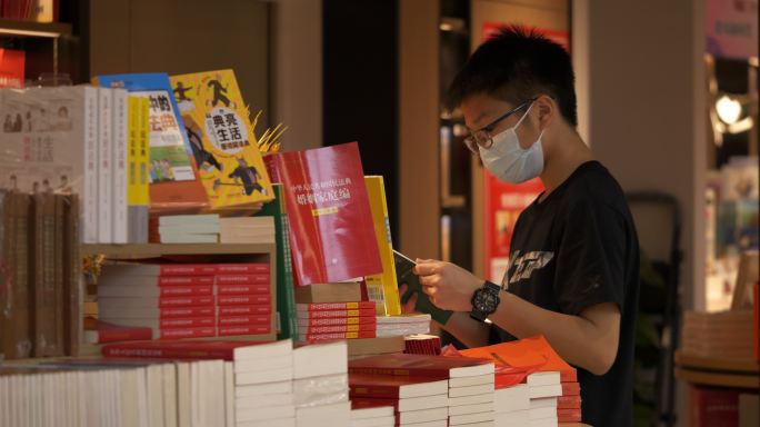 一个带口罩的学生在书店看书