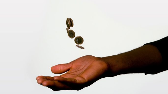 Businessman catching falling coins in hand in slow