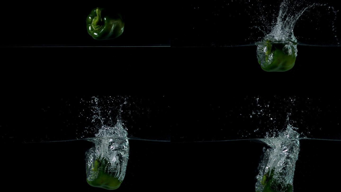 青椒在黑色背景的慢镜头中落入水中