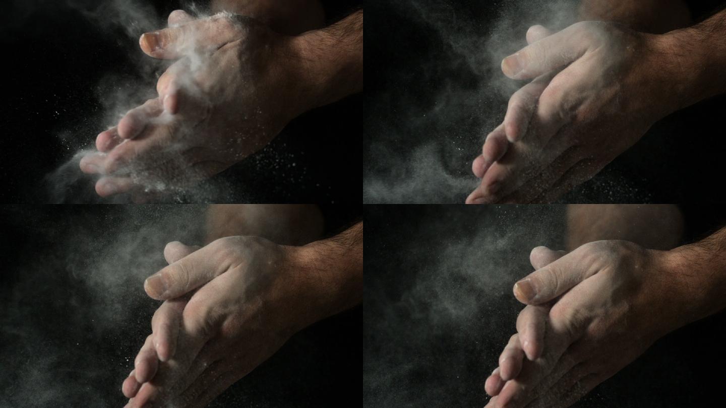 在慢镜头中，面包师的手在黑色背景上拍打面粉