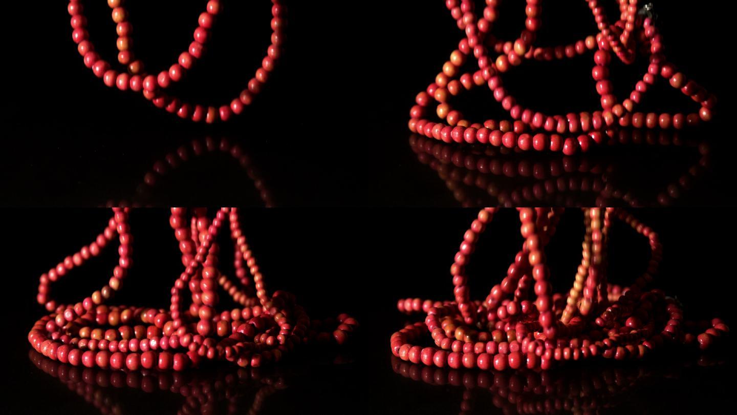 在慢镜头中，红色的念珠落在黑色的背景上