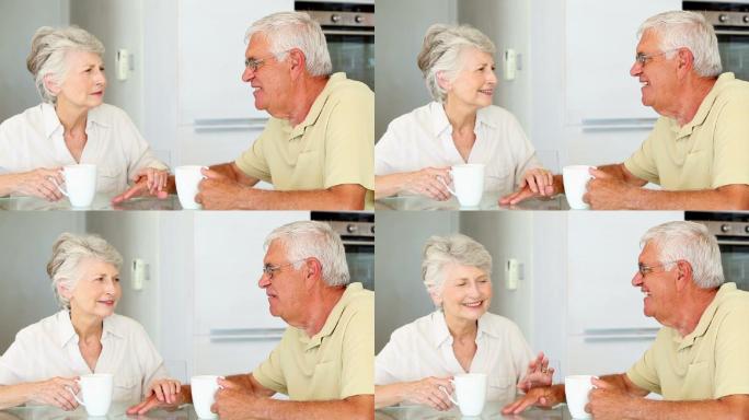 老夫妇坐在桌子旁，在厨房里喝咖啡