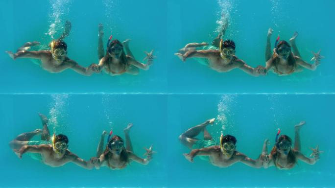 在慢镜头中，一对夫妇戴着通气管把海星抱在水下
