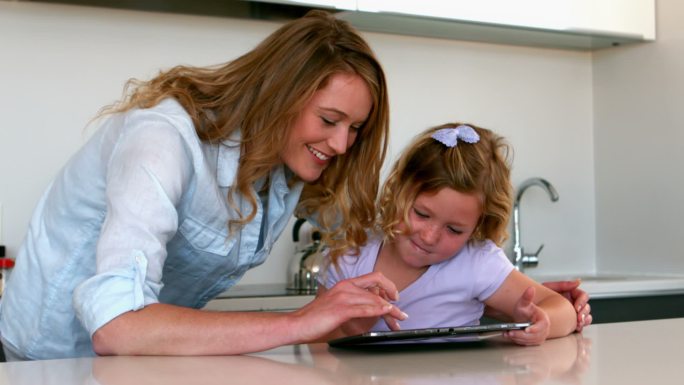 母亲和女儿在厨房里用平板电脑的慢镜头