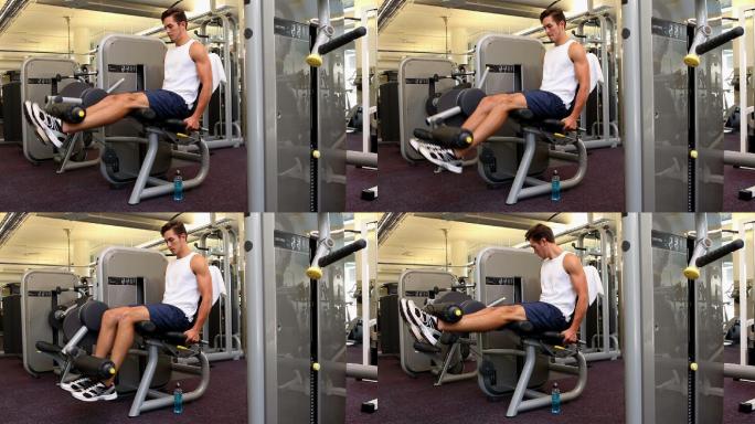 健身的人在健身房的举重机上锻炼他的腿