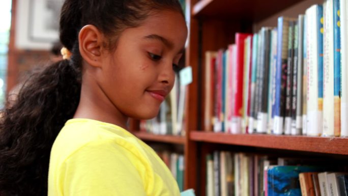 小学图书馆里的小女孩对着镜头微笑