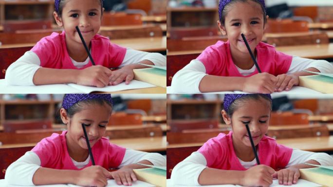 可爱的小女孩涂色书在教室里对着镜头微笑在小学