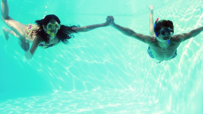 一对快乐的情侣在他们的假期里一起穿着通气管在游泳池里跳