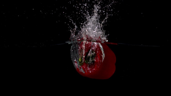 红色辣椒落入水中，在黑色背景下