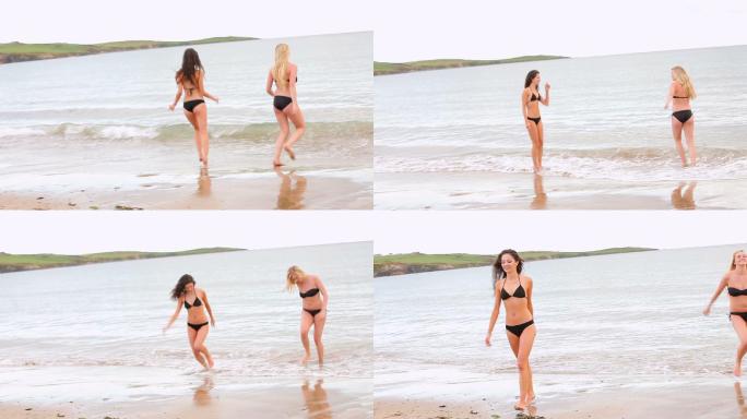 两个朋友在海滩冰冷的海水中来回奔跑