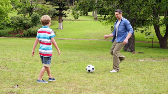 在一个阳光明媚的日子里，父亲和儿子在踢足球