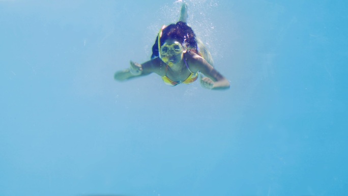 黑发女子在度假时戴着通气管跳进游泳池