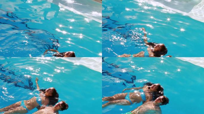 一对夫妇在一个阳光明媚的日子里漂浮在游泳池里