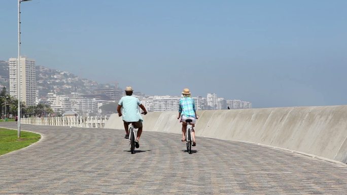 一对夫妇在一个阳光明媚的日子去海边骑自行车