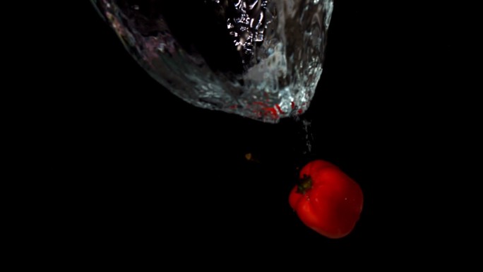 红色辣椒落入水中，在黑色背景下