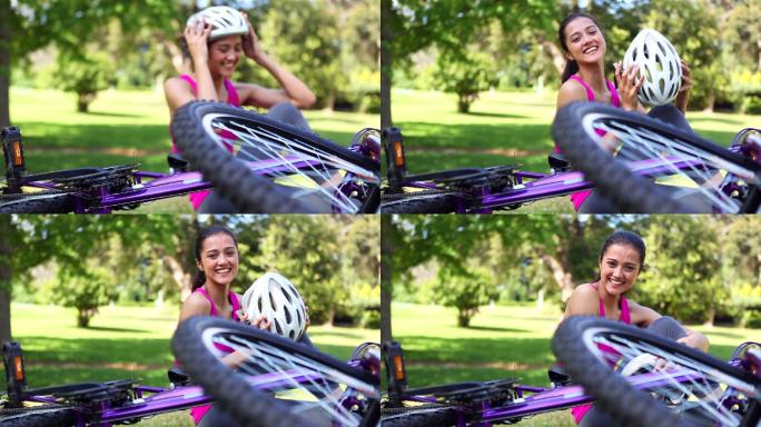 Fit女孩脱下她的自行车头盔对着相机微笑在一个阳光明媚的日子