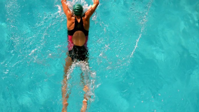 健康的女人在室外游泳池游泳在头顶的慢动作