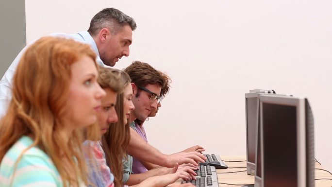 在大学计算机室与讲师一起工作的学生