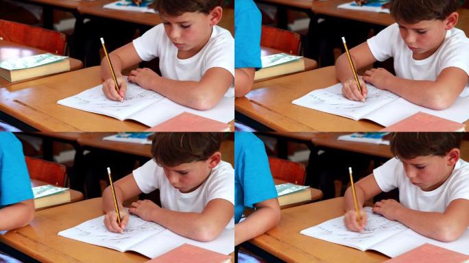 小男孩在小学教室里用记事本画画