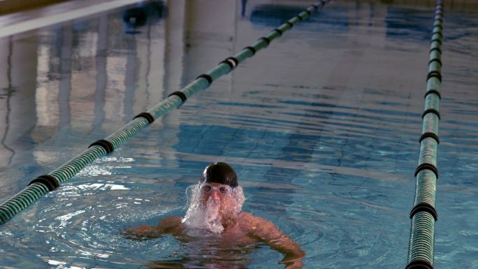 健康的游泳者在游泳池中以慢动作跳起来欢呼