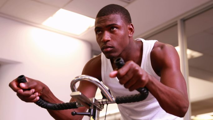 在健身房里骑着自行车健身的壮汉