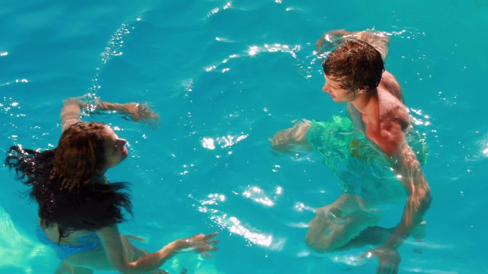 幸福的夫妇在他们的假期在游泳池里玩得很开心