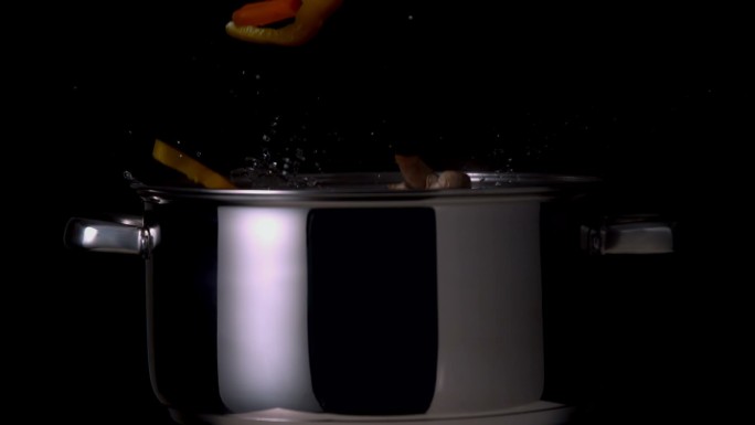 蔬菜落入锅在黑色背景的慢镜头
