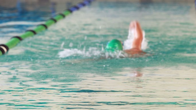 健康的游泳者在休闲中心的游泳池里做仰泳