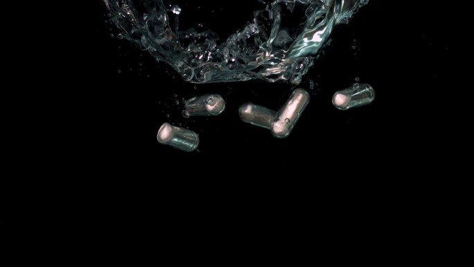 白色药丸落在水中的慢镜头黑色背景