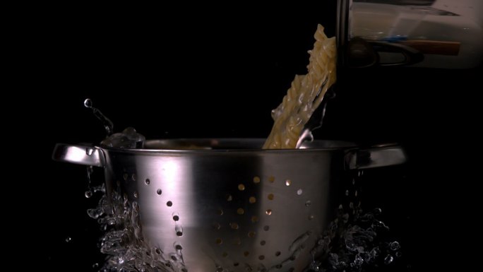 用漏勺慢动作将意大利面和水倒入锅中