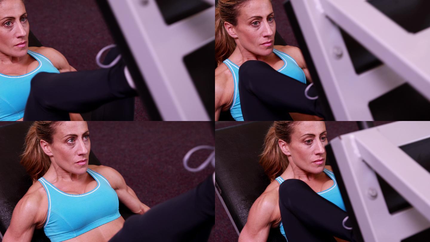 超级健康的女人在健身房使用腿部举重机