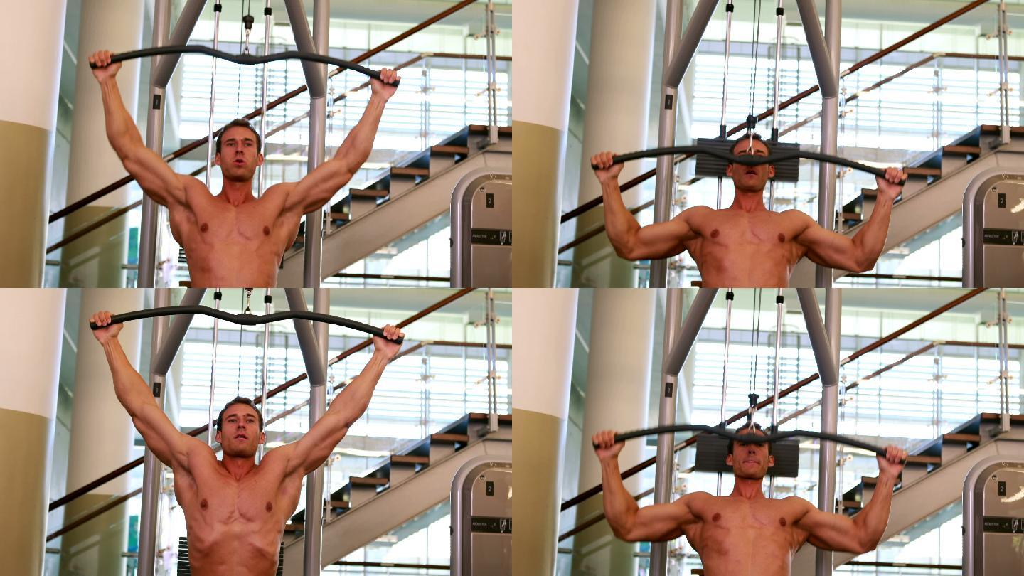 肌肉发达的男人在健身房的举重机上锻炼手臂