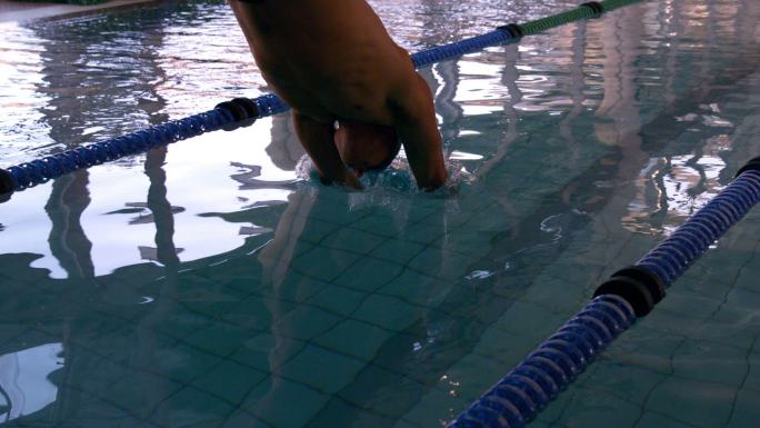 健康的游泳运动员以慢动作跳入游泳池