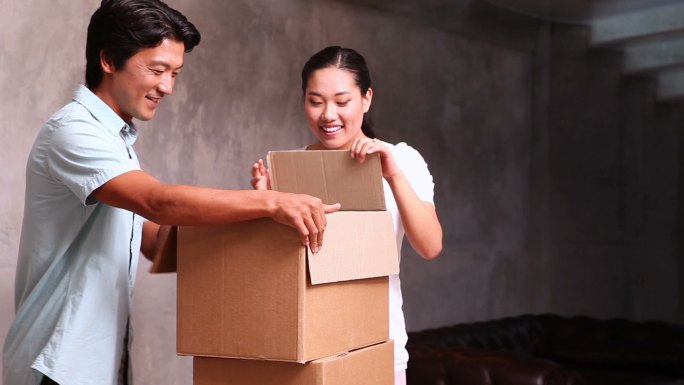 年轻的亚洲夫妇在他们的新家打开移动箱子