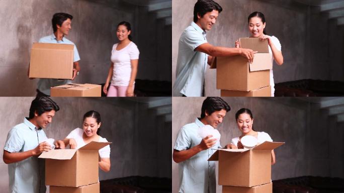 年轻的亚洲夫妇在他们的新家打开移动箱子