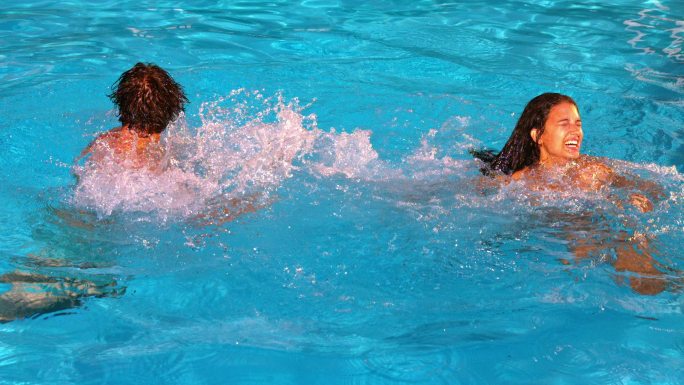 一对夫妇在游泳池里玩水花和慢动作