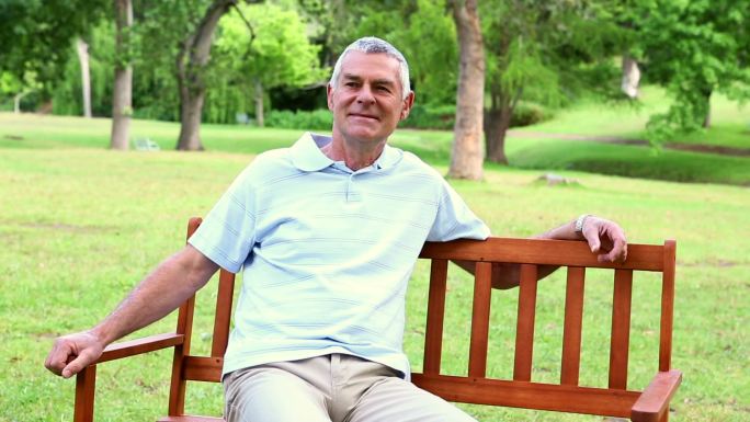 一个阳光明媚的日子，退休男子在公园的长椅上休息