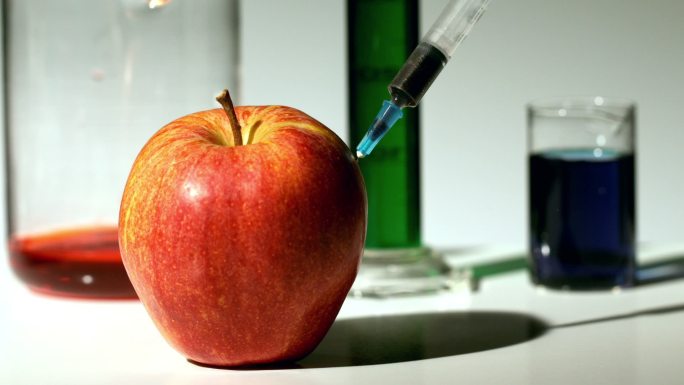 用注射器将化学物质慢动作注入苹果