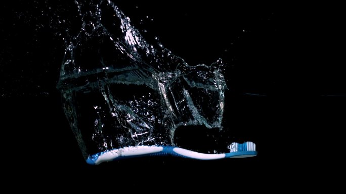 蓝色牙刷在黑色背景下的慢镜头掉进水中