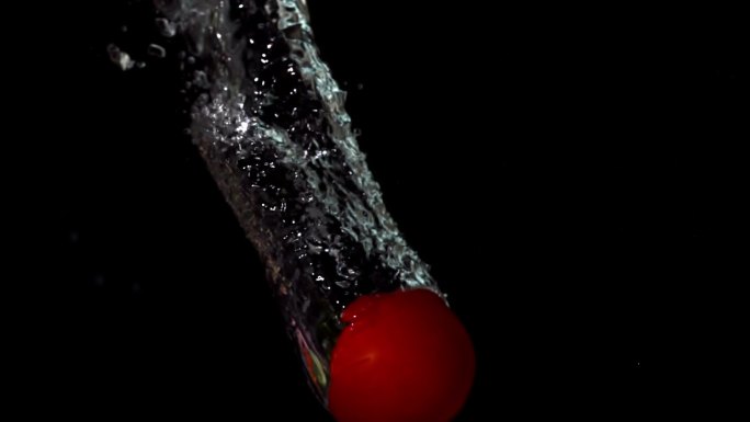 在慢动作的黑色背景下，番茄落在水中