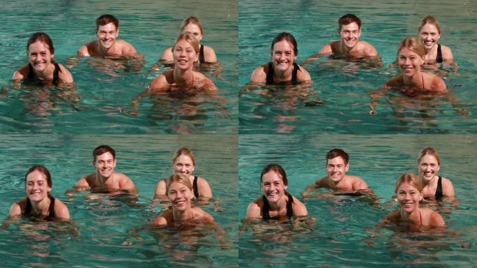 四个微笑的人在休闲中心的游泳池里做水中有氧运动