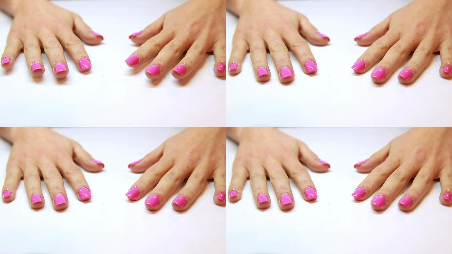 在美甲沙龙展示了新鲜的粉红色指甲的手