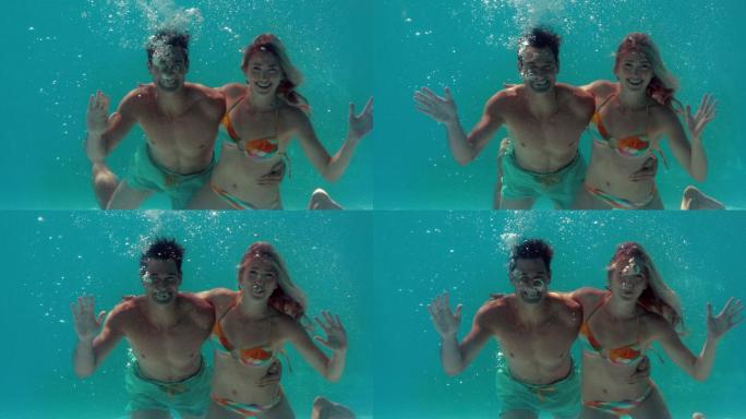 一对夫妇在游泳池里用慢镜头向镜头挥手