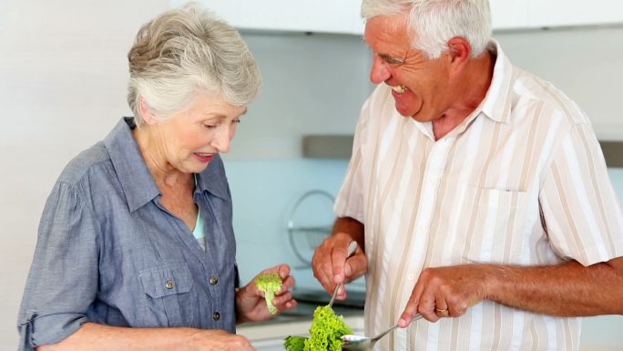 一对老年夫妇正在厨房里准备健康沙拉