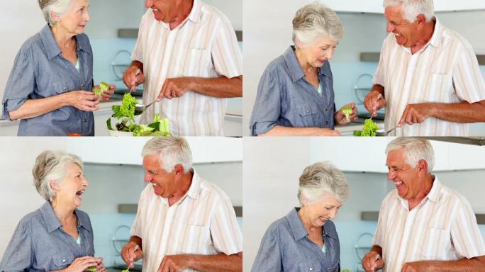 一对老年夫妇正在厨房里准备健康沙拉