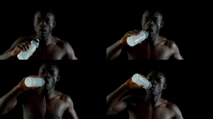 赤膊男子慢跑和饮用水的黑色背景在慢镜头